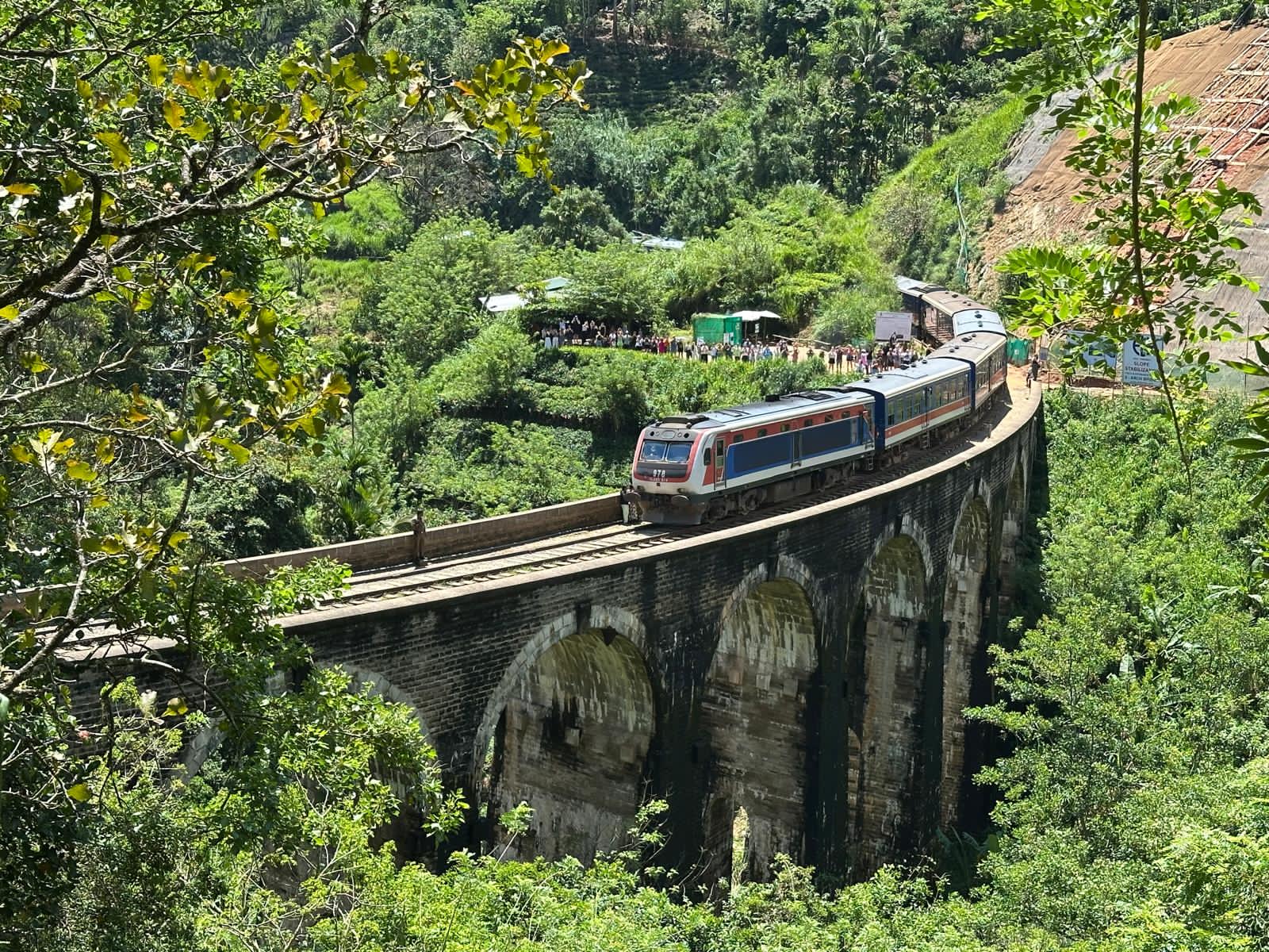 A train crossing a stone bridge in the green Sri Lankan highlands