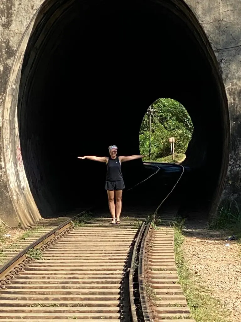 Traveller standing beneath an arch of Nine Arch Bridge near Ella